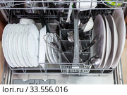 Opened dishwasher with clean plates, spoons is in the kitchen, close up view. Стоковое фото, фотограф Кекяляйнен Андрей / Фотобанк Лори