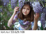 Красивая девочка в парке возле цветущей глициниеи. Стоковое фото, фотограф Марина Володько / Фотобанк Лори