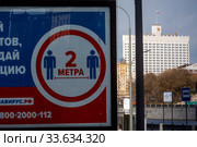 Информационный плакат с требованием соблюдать социальную дистанцию в городе Москве на фоне здания Правительства РФ во время эпидемии коронавируса COVID-19 в России (2020 год). Редакционное фото, фотограф Николай Винокуров / Фотобанк Лори