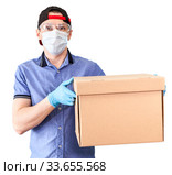 Caucasian deliveryman wearing plastic glasses, medical mask and blue neoprene gloves holding cardboard, isolated on white background. Стоковое фото, фотограф Кекяляйнен Андрей / Фотобанк Лори