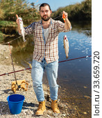 Positive fisherman holding catch freshwater fish in hands. Стоковое фото, фотограф Яков Филимонов / Фотобанк Лори