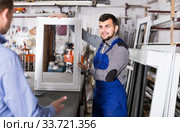 Production worker in coverall demonstrating different PVC windows to customer. Стоковое фото, фотограф Яков Филимонов / Фотобанк Лори