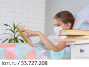 Заболевшая гриппом девочка читает книгу, на тумбочке перед ней лежат книги, фокусировка на девочку. Стоковое фото, фотограф Иванов Алексей / Фотобанк Лори