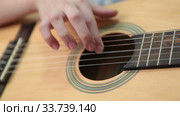 Hand pluck the strings and fretboard of a yellow acoustic guitar, close up view (2020 год). Редакционное видео, видеограф Кекяляйнен Андрей / Фотобанк Лори