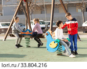 Company of kids are teetering on the swing on the playground. Стоковое фото, фотограф Яков Филимонов / Фотобанк Лори