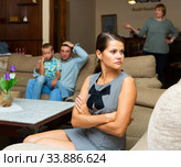 Upset woman sitting during quarrelling between family on background. Стоковое фото, фотограф Яков Филимонов / Фотобанк Лори