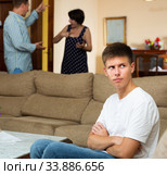 Parents swear among themselves. Offended son sits on a sofa. Стоковое фото, фотограф Яков Филимонов / Фотобанк Лори