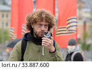 Блогер Илья Варламов снимает смартфоном на улице праздничной Москвы (2020 год). Редакционное фото, фотограф Free Wind / Фотобанк Лори