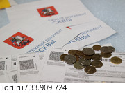 Российские монеты и купюры и калькулятор лежат на квитанциях для оплаты коммунальных услуг. Стоковое фото, фотограф Кузнецов Максим / Фотобанк Лори