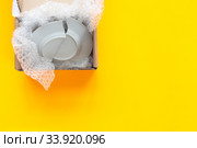 На желтом фоне лежит открытая посылка, коробка с разбитой тарелкой. Стоковое фото, фотограф Иванов Алексей / Фотобанк Лори