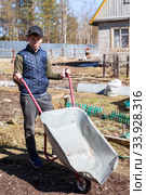 Юноша с пустой тачкой на огороде. Стоковое фото, фотограф Кекяляйнен Андрей / Фотобанк Лори