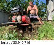Мужчина культивирует землю мотоблоком (вспашка огорода). Рыхление земли при помощи мотоблока. Стоковое фото, фотограф Кузнецов Максим / Фотобанк Лори