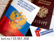 Брошюра Конституции Российской Федерации паспорт и гаджет с открытым заявлением на дистанционное участие в общероссийском голосовании 1 июля 2020 года лежат на деревянном столе. Редакционное фото, фотограф Николай Винокуров / Фотобанк Лори