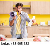 Young man calculating expences for vegetables in kitchen. Стоковое фото, фотограф Elnur / Фотобанк Лори