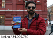 Иностранец держит в руках брошюру конституции Российской Федерации (2020 год). Редакционное фото, фотограф Кузнецов Максим / Фотобанк Лори