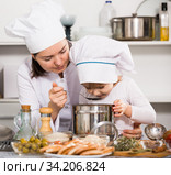 Mother and her young daughter in uniform are tasting the soup together. Стоковое фото, фотограф Яков Филимонов / Фотобанк Лори