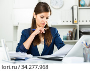 Upset woman working with laptop and papers at the office. Стоковое фото, фотограф Яков Филимонов / Фотобанк Лори