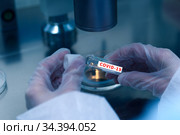 Closeup of microbiologist's hand opening test tube with coronavirus vaccine. Стоковое фото, фотограф Pavel Biryukov / Фотобанк Лори