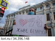 Девушка держит плакат с надписью на белорусском "Жыве Беларусь!" на фоне здания посольства Республики Беларусь в Москве, Россия (2020 год). Редакционное фото, фотограф Николай Винокуров / Фотобанк Лори