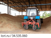 Flat grain storage capacity with sweeper tractor, grain warehouse or clean span granary. Стоковое фото, фотограф Кекяляйнен Андрей / Фотобанк Лори
