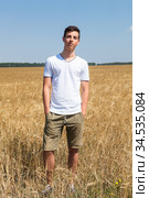 Handsome teen age fellow with hands in pockets standing on an agricultural field, full-length portrait. Стоковое фото, фотограф Кекяляйнен Андрей / Фотобанк Лори