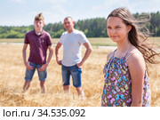 Pretty girl in summer light dress portrait with her father and brother on background, Caucasian family in wheat field. Стоковое фото, фотограф Кекяляйнен Андрей / Фотобанк Лори