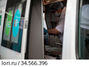 Медицинский работник проводит вакцинацию в специальном автомобиле скорой помощи мобильного пункта бесплатной вакцинации от гриппа на Тверской улице у метро в центре города Москвы, Россия (2020 год). Редакционное фото, фотограф Николай Винокуров / Фотобанк Лори