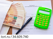 На столе лежит договор купли продажи земельного участка, пачка денег в конверте, ручка и калькулятор. Стоковое фото, фотограф Иванов Алексей / Фотобанк Лори