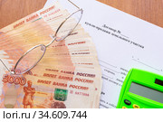 На столе лежит договор купли продажи земельного участка, пачка денег, калькулятор и очки. Стоковое фото, фотограф Иванов Алексей / Фотобанк Лори
