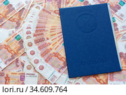 На фоне из пятитысячных купюр лежит диплом о высшем образовании. Стоковое фото, фотограф Иванов Алексей / Фотобанк Лори