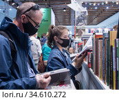 Посетители Московской международной книжной ярмарки у полок с книгами (2020 год). Редакционное фото, фотограф Сайганов Александр / Фотобанк Лори