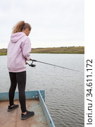 Pre-teen girl standing with fish rod, female fisherman catching the fishes from pier. Стоковое фото, фотограф Кекяляйнен Андрей / Фотобанк Лори