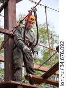 Portrait of cute preteen age girl climbing in adventure park, standing on altitude and looking at camera. Стоковое фото, фотограф Кекяляйнен Андрей / Фотобанк Лори