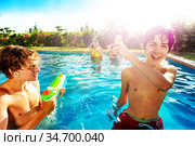 Group of friends in swim pool shooting water-gun. Стоковое фото, фотограф Сергей Новиков / Фотобанк Лори