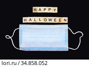 Medical mask and wooden words Happy Halloween on black. Halloween background decor holiday concept. Стоковое фото, фотограф Papoyan Irina / Фотобанк Лори