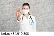 Doctor woman makes stopping hand gesture. Girl Doctor wearing protection face mask against covid-19. Banner panorama medical staff preventive gear about coronavirus. Woman in medical mask stops nCov. Стоковое фото, фотограф Сергей Тимофеев / Фотобанк Лори