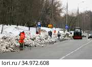 Рабочие в оранжевой спецодежде убирают снег. Автобусная остановка маршрута 674. Москва, Днепропетровская улица (2011 год). Редакционное фото, фотограф Щеголева Ольга / Фотобанк Лори