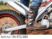 Close up view at rider's motocross boot standing on peg of dirt motorcycle. Safety apparel for riding. Стоковое фото, фотограф Кекяляйнен Андрей / Фотобанк Лори
