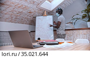 An online maths lesson - an african-american man teacher in medicine mask standing by the board and explains the material for his students in front of the laptop. Стоковое видео, видеограф Константин Шишкин / Фотобанк Лори