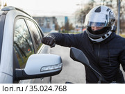 Motorcyclist beat side-view mirror of car with a fist, conflict is on the road. Стоковое фото, фотограф Кекяляйнен Андрей / Фотобанк Лори