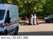 Врачи надевают защитный костюм перед посещением пациента с новой коронавирусной инфекцией. Вызов врача на дом. COVID-19. Москва, Россия (2020 год). Редакционное фото, фотограф ирина реброва / Фотобанк Лори