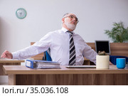 Old male employee suffering from radiculitis at workplace. Стоковое фото, фотограф Elnur / Фотобанк Лори