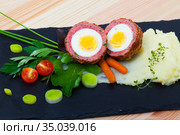 Dishes of traditional Scottish cuisine of scotch egg served with greens and potatoes. Стоковое фото, фотограф Яков Филимонов / Фотобанк Лори
