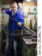 Confident gunsmith lubricates and cleans barrel of rifled shotgun. Стоковое фото, фотограф Яков Филимонов / Фотобанк Лори
