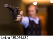 Smallbore sporting pistol in hand of man training in shooting range. Стоковое фото, фотограф Яков Филимонов / Фотобанк Лори