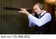 Confident shooter sighting in or zeroing shotgun in shooting gallery. Стоковое фото, фотограф Яков Филимонов / Фотобанк Лори
