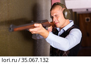 Confident shooter sighting in or zeroing shotgun in shooting gallery. Стоковое фото, фотограф Яков Филимонов / Фотобанк Лори