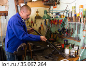 Confident gunsmith lubricates and cleans barrel of rifled shotgun. Стоковое фото, фотограф Яков Филимонов / Фотобанк Лори