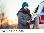Positive Caucasian female driver portrait with opened gas cap lid of her car, looking at camera. Стоковое фото, фотограф Кекяляйнен Андрей / Фотобанк Лори