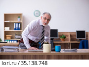 Old male employee suffering from radiculitis at workplace. Стоковое фото, фотограф Elnur / Фотобанк Лори